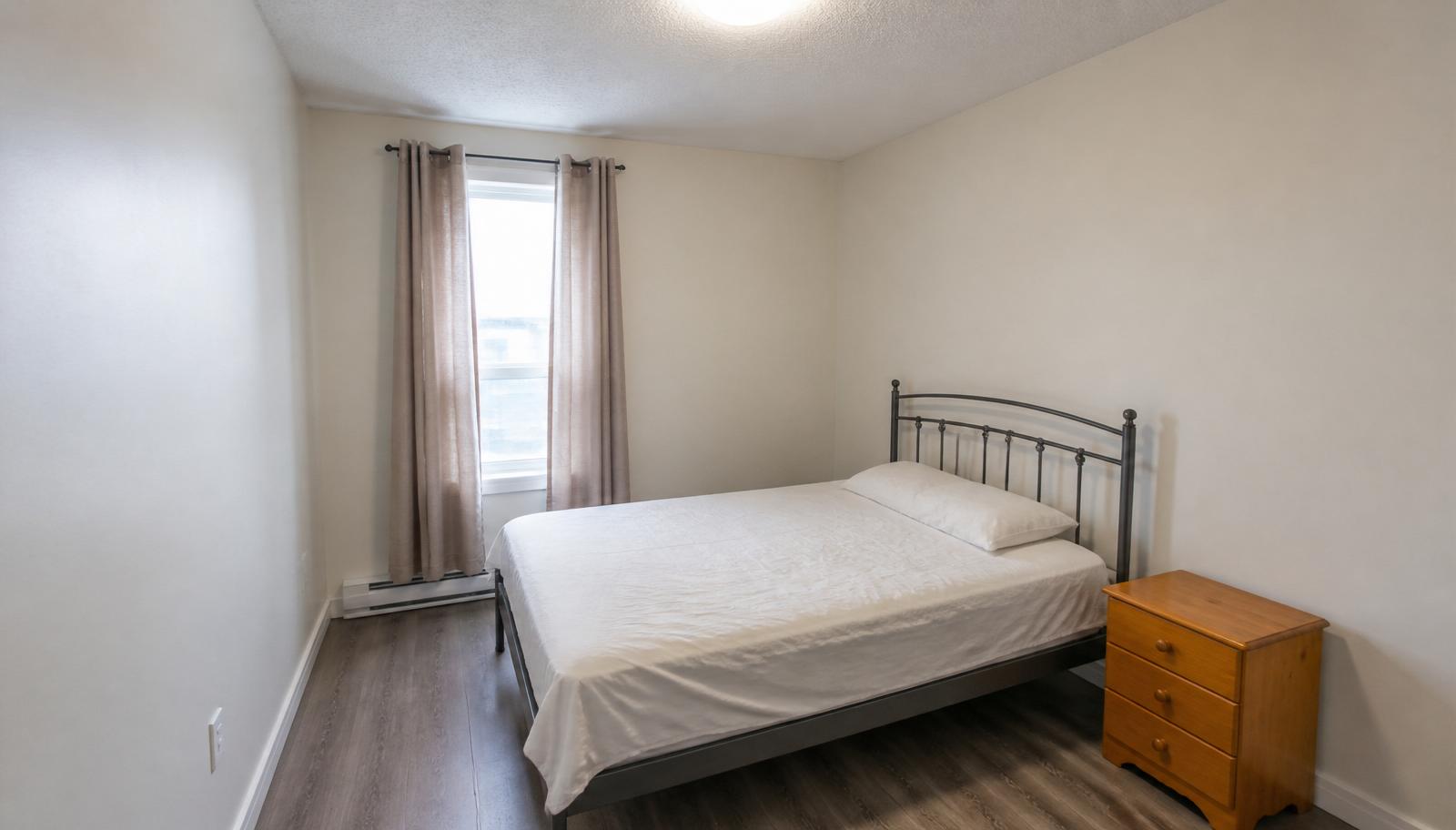 Plain bedroom with metal frame bed, cheap curtains and pine nightstand before AI bedroom redesign